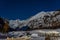 Cogne, Aosta Valley, snowy path on a full moon night with starry sky and mountains in the background