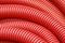 Coil of red plastic corrugated plumbing pipe