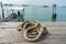 A coiled rope on wooden pier, sea and boat are background