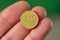 coin face of 10 euro cents in the fingers of the hand.  green background.