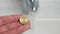 Coin in hand and water tap in the bathroom.