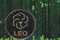 Coin  Leo bitfinex cryptocurrency on the background of binary crypto matrix text and price chart.