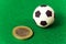 Coin one euro and a souvenir soccer ball on a green background. Concept money and sports, betting on football, corruption and earn