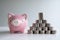 Coin and pink piggy bank with coins pyramid, step up growing business to success and saving for retirement concept