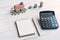 Coin stack with house model and notebook for copy space and calculator, savings plans for housing financial concept