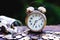 Coin stacks arranged into business cycle step, up and down, and vintage alarm clock on wooden table with morning light