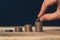 Coin stacks closeup with hand putting an US quarter on the top of the highest pile. Financial and business growth, economics,