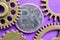 The coin with the symbol of the Russian ruble is surrounded by gears made of brass