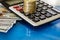 Coins on a calculator and dollars on a blue reflective background. Close-up.