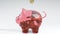 Coins fall into a pink glass piggy bank - a symbol of wealth, frugality and effective investment planning. Symbol of financial suc