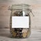 Coins in glass money jar with white blank label