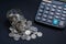 Coins scattered with glass jars and calculator on a dark background