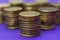 Coins stand on pillars on a background of violets.