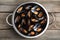 Colander with delicious cooked mussels on wooden table, top view