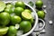 Colander with fresh ripe limes and ice cubes