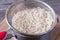 Colander with rice in saucepan on wooden board