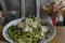 Cold appetizer, zucchini pasta with greens and feta. Vegetarian option. The girl in one hand knife, in the other the sauce for the