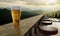 Cold beer in a clear glass bubble and beer foam Put on a long wooden table On the restaurant terrace on the mountain. The