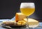 Cold belgian beer in glass served in cafe with variety of hard cheeses, tasty european food