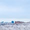 Cold blue sky over town and snow woods in winter