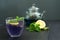 Cold blue Thai Anchan tea in a glass cup with ice and a transparent teapot. Copy space