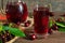 Cold cherry juice in a glass and pitcher with cherries inside on wooden tablr