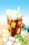 Cold cola or ice tea with lemon on beach background