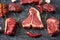 Cold cuts - raw, aged, juicy steaks of filet mignon, t-bone, ribeye, striploin, on a dark stone background with rosemary sprigs