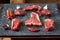 Cold cuts - raw, aged, juicy steaks of filet mignon, t-bone, ribeye, striploin, on a dark stone background with rosemary sprigs