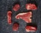 Cold cuts - raw, aged, juicy steaks of filet mignon, t-bone, ribeye, striploin, on a dark stone background. Top view, assortment