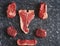 Cold cuts - raw, aged, juicy steaks of filet mignon, t-bone, ribeye, striploin, on a dark stone background. Top view, assortment