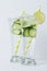 Cold detox water with slices cucumber decorated pieces lime and straw on white wood board.