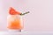 Cold fresh homemade lemonade of fresh grapefruit juice and ice cubes decorated slice citrus and twig rosemary on pastel pink.