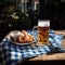 Cold full beer mug with Beirian pretzels on the wooden table covered with traditional blue and white tablecloth during Oktoberfest