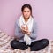 A cold girl sitting on the bed with a cup of tea