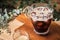 Cold iced black brew coffee in a glass with pieces of ice on a wooden table, natural light, fresh summer drink