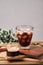 cold iced black brew coffee in a glass with pieces of ice on a wooden table, natural light, fresh summer drink