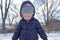 Cold little girl with rosy cheeks playing in the snow