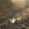 Cold misty Winter landscape over stream in English countryside