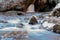 Cold mountain river flows between stones with snow and ice, selective focus, waterfall in the background, long exposure, Karachay-