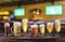 Cold mugs and glasses of beer on the old wooden table. Blurred pub interior at the background. Assortment of beer