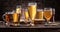 Cold mugs and glasses of beer on the old wooden table, brick wall at the background. Assortment of beer