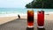 Cold Orange and Raspberry Cocktails on Table on Beach, Sunny Sea on Background