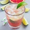 Cold pink cocktail with fresh grapefruit, lime and ice cubes on concrete background, paloma, square