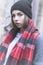 Cold portrait of a young attractive girl in a cap coat and red scarf in the cold season