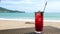 Cold Red Mocktail With Berries on Beach Table, Defocused Sea Waves on Background