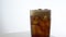 Cold refreshing cola pouring into a glass with ice on white background with space for text. Icy beverage of cool drink with