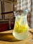 Cold refreshing limonade, mojito or gin tonic in glass, with fresh mint and ice cubes, lime and lemon on wooden table