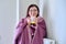 Cold season, woman with plaid mug of hot tea warming near wall heating radiator