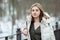 Cold season young beautiful woman in white coat with disheveled hair posing on park bridge lifestyle concept portrait